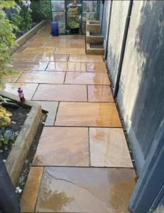 Newly installed autumn brown Indian flagstone patio with raised flower beds by Drivers Building & Roofing.