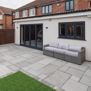 Modern extension with sliding glass doors and a stone-paved patio built by Drivers Building & Roofing.